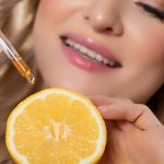 A C-vitamin vitalizálja a bőrt Közeli fotó női arcról, mely előtt egy félbevágott citrom és egy pipetta van.