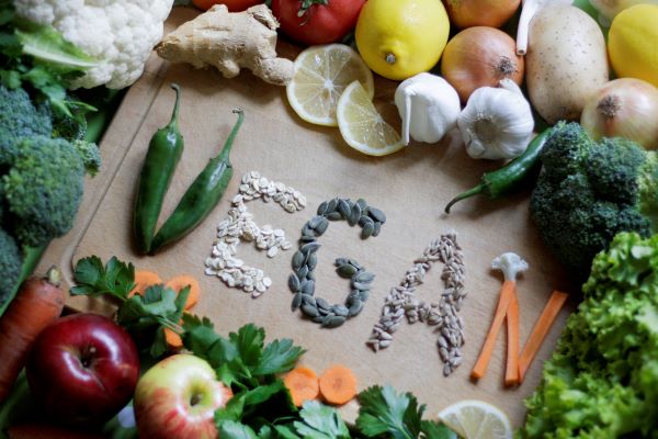 Körben zöldségek és gyümölcsök, középen zöldségekből és magvakból kirakva a "vegán" szó.