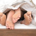 Takaró alól kikandikáló férfi- és női lábfejek.