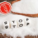 Asztalra kiszórt kristálycukor, fakanálban cukor, fehér betűkockákból kirakott "stop" szó, kis stoptábla.