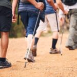 Négy ember deréktól lefelé, ahogy bottal sétálnak (nordic walking).