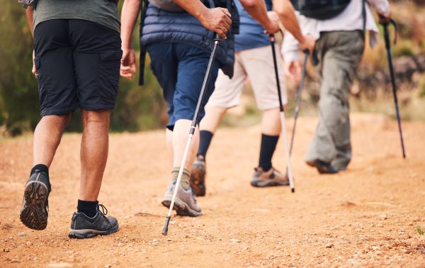 Négy ember deréktól lefelé, ahogy bottal sétálnak (nordic walking).