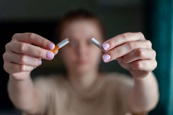 Nő kettétör egy cigarettát.