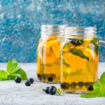 Két pohár tea áfonyaszemekkel és citromdarabokkal, mentalevéllel.