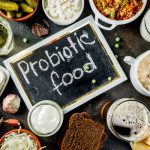 Prebiotikumok, probiotikumok, emésztőenzimek és D-vitamin IBS ellen Különböző probiotikus ételek felülről fotózva, középen fekete táblán fehér felirat: "probiotic food".
