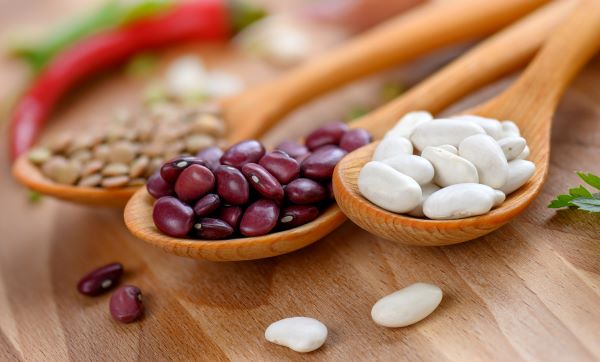 Három fakanálban fehér bab, vörös bab és lencse.