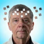 Idős férfi feje körül puzzle-darabok, kék háttérrel.