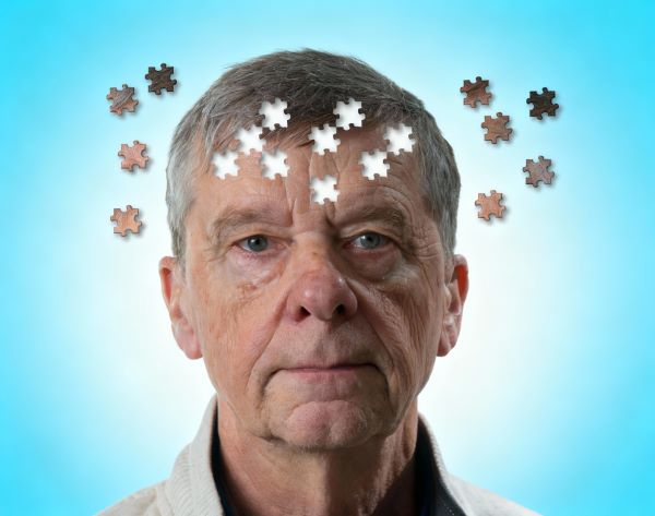 Idős férfi feje körül puzzle-darabok, kék háttérrel.
