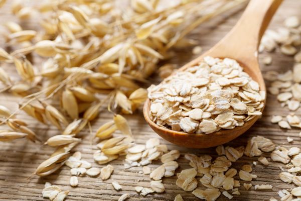 Fakanálban zabpehely, mellette gabonaszálak.