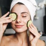 Nő a csukott szemére helyez uborkaszeletet.