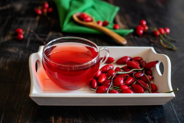 Egy csésze csipkebogyótea, mellette csipkebogyók.