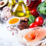 Gyulladást csökkentenek, védenek a betegségek ellen Konyhapulton különböző egészséges táplálékok: halszelet, dió, mandula, avokádó, olívaolaj, paradicsom, kurkuma, fokhagyma, gyömbér, spenótlevelek, bab.