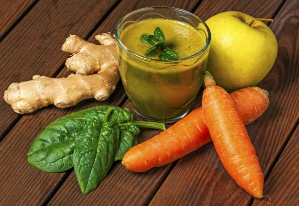 Faasztalon egy pohár turmixital, mellette sárgarépa, spenót, gyömbér, alma.