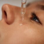 Női arc közelről, amelyre egy pipettából szérumot csepegtetnek.