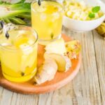 Faasztalon két pohár ital szívószállal, mellette ananász- és gyömbérdarabok.