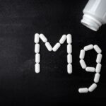 Fekete háttéren fehér kapszulákból kirakva a magnézium vegyjele: Mg.