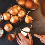 Valaki hagymát vág egy sötét konyhapulton.