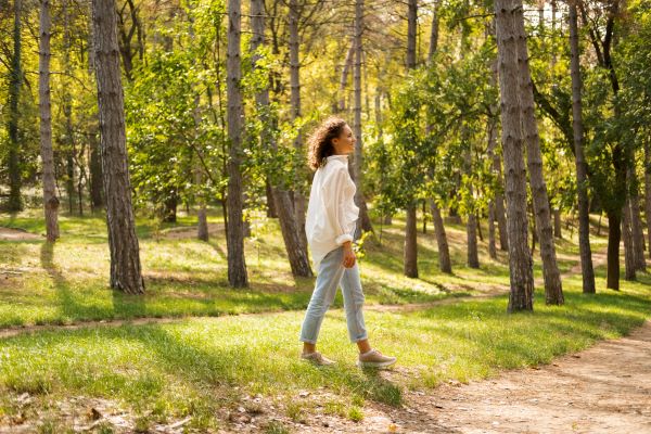 Fiatal nő sétál az erdőben.