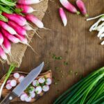 Faasztalon egy csomó piros retek és újhagyma, vágódeszka késsel.