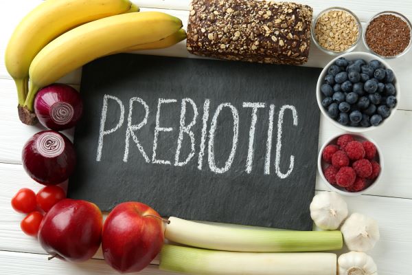 Fehér faasztalon különböző élelmiszerek, középen fekete táblán krétafelirat: "prebiotic".