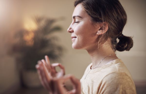 Nő csukott szemmel ülve meditál.