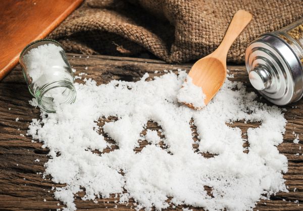 Faasztalon kiszórva sok durva szemcséjű só, "beleírva" a "salt" szó, mellette felborult sótartó, fakanál.
