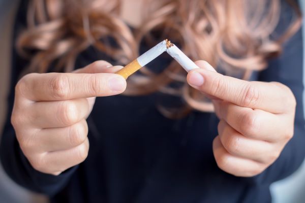 Nő kettétör egy cigarettát.
