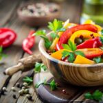 Fatálban csíkokra vágott sárga és piros paprika, mellette borsszemek.