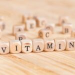 Faasztalon kis betűkockákból kirakva a "vitamin" szó, mögötte elszórtan különböző betűkockák: A, B, C, D, E.