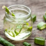 Faasztalon egy kis befőttesüvegben Aloe vera gél szívószállal, benne és körülötte Aloe vera darabok.