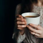 Kávé – életmentő ital vagy rejtett függőség? Nő egy csésze kávét tart a kezében.